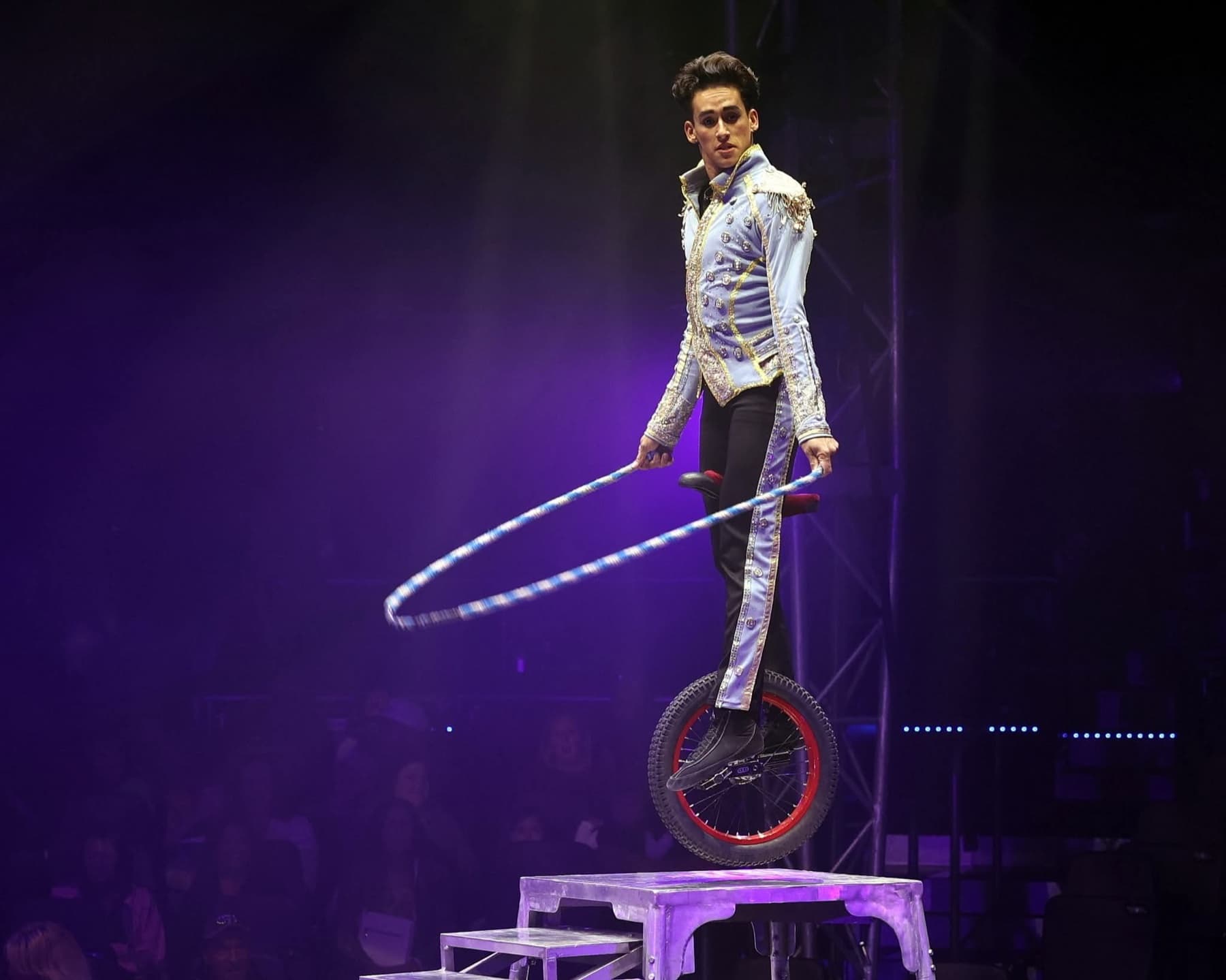 A unicyclist spinning a hoop on a raised platform